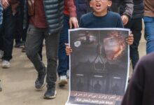 Palestinian boy holds protest poster against Israeli death penalty law in Gaza.