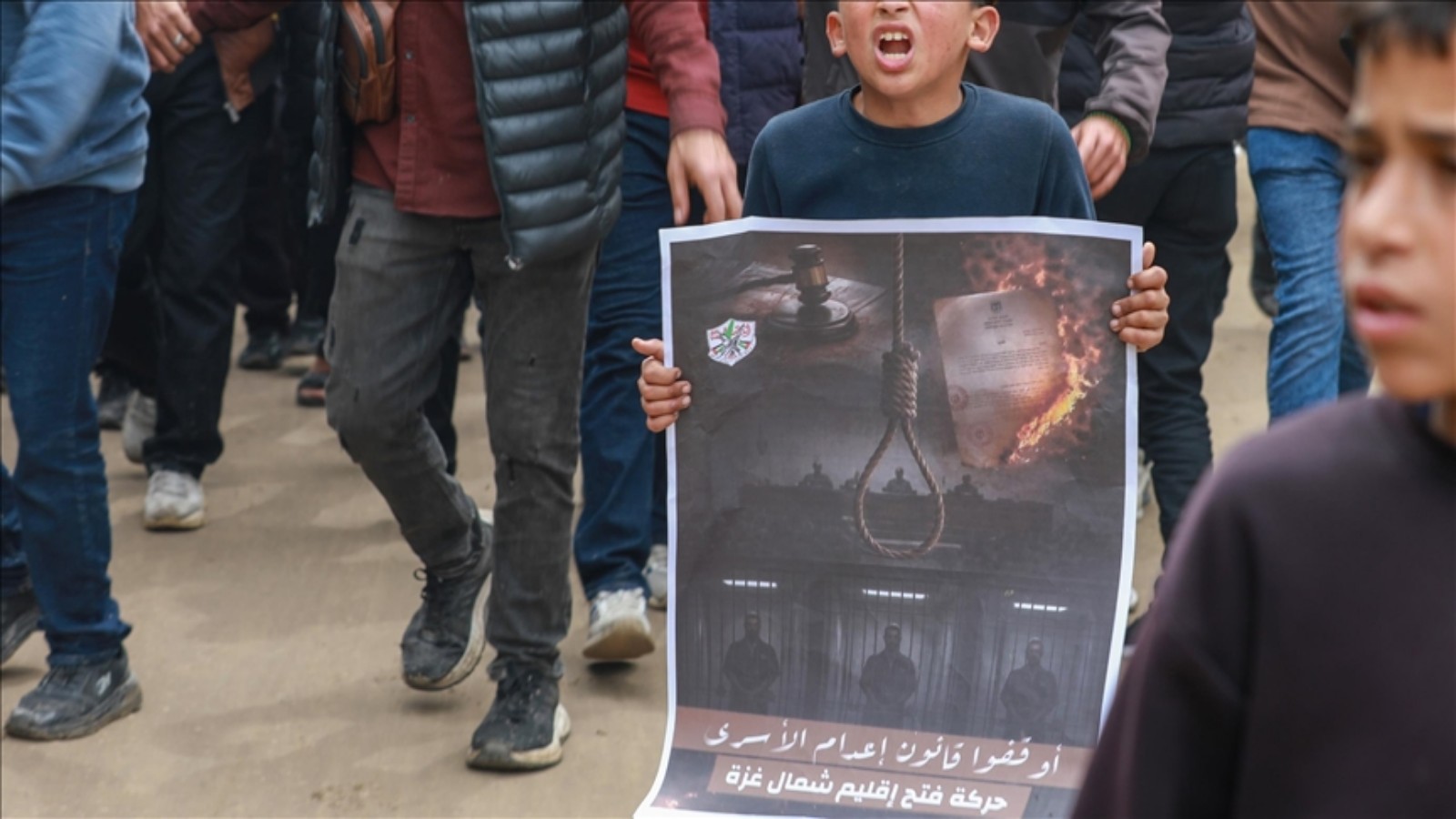 Palestinian boy holds protest poster against Israeli death penalty law in Gaza.