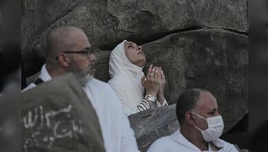 Pilgrims gather on Mount Arafat as a woman raises her hands in prayer during the annual Haj pilgrimage on June 5, 2025.