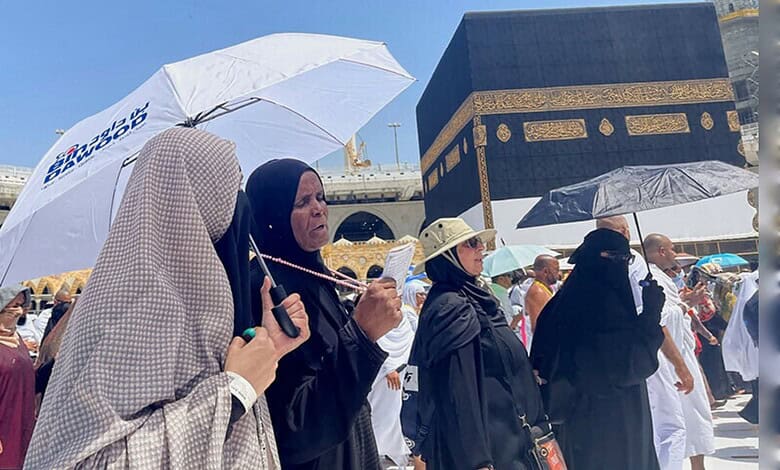 Pilgrims at the Kaaba during summer, with umbrellas for shade, as they perform religious rites in the his.