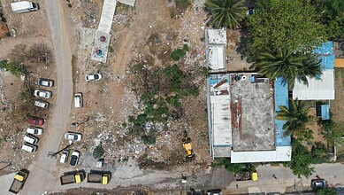 Aerial view of Hydraa removing encroachments around a pond in an urban area. The process involves clearin.