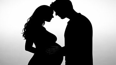 Silhouette of a pregnant Bollywood couple facing each other, highlighting their anticipation of a second.
