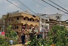 Fallen tree branches and power lines caused by unseasonal rain, leading to power outages and water supply disruptions in Hyderabad.
