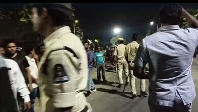Crowd and police presence in Rajendranagar following mosque desecration. Tense atmosphere with residents.