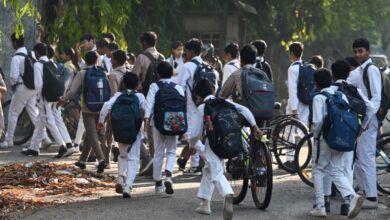 Image shows A group of uniformed Indian school children with backpacks walk and cycle along a tree-lined path.