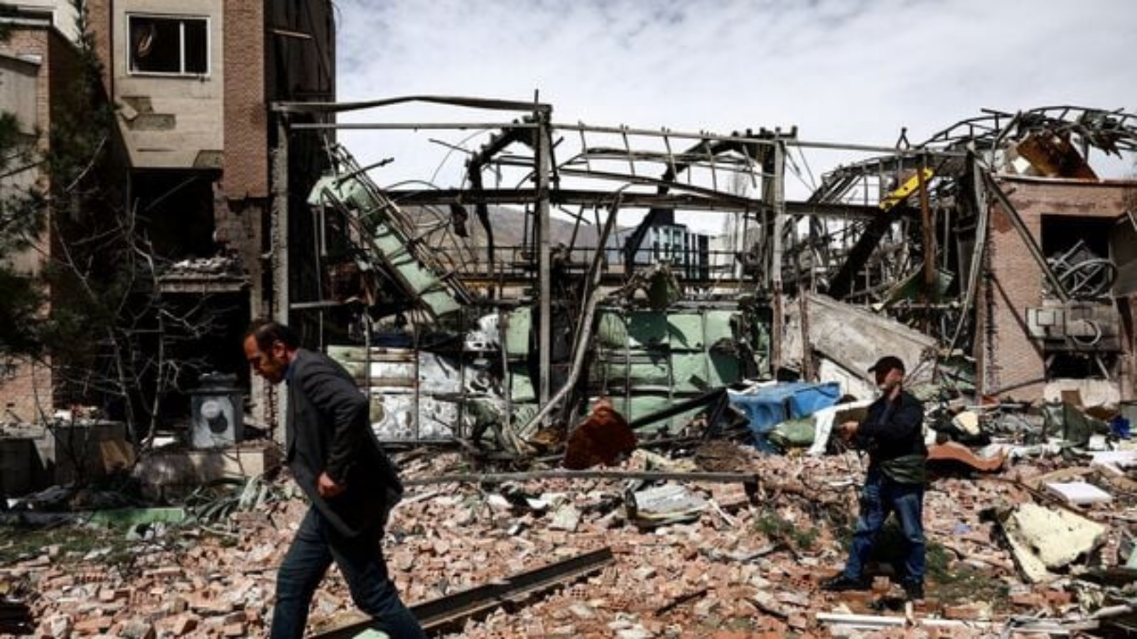 People walk past debris and inspect damage at a destroyed research building at Shahid Beheshti University in Tehran following a strike on April 4, 2026.