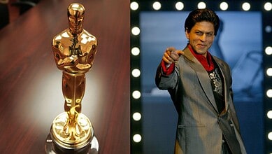 Shah Rukh Khan reacts as he receives an Oscar honour, standing confidently on stage.