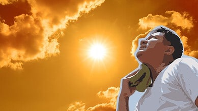 Person relaxing outdoors during sunset with a vibrant sky and clouds in the background.