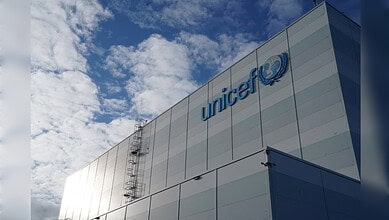 UNICEF logo on a modern building facade against a blue sky with clouds.