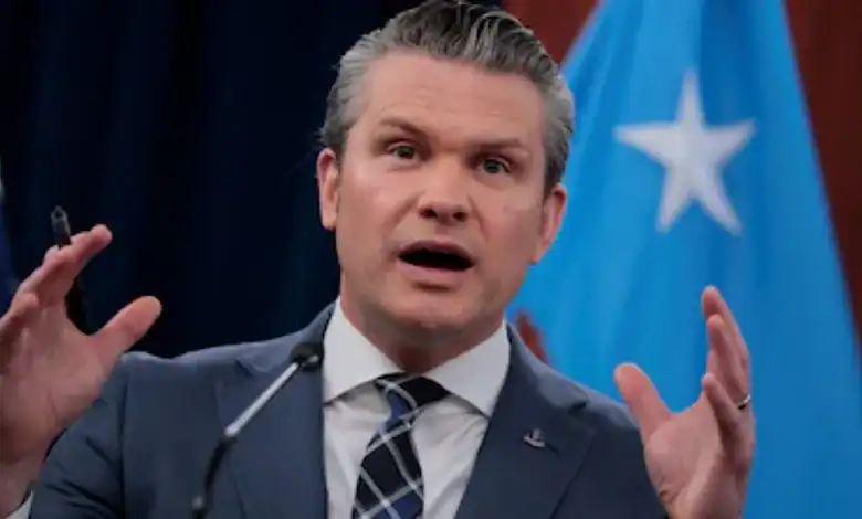 US Defence Secretary Pete Hegseth speaks during a press briefing with US and Somali flags in the background.
