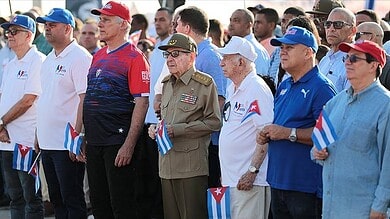 Cuban citizens and officials gather holding small Cuban flags during a public event.