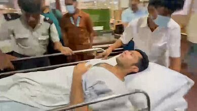 A patient lying on a hospital bed surrounded by medical staff and visitors.