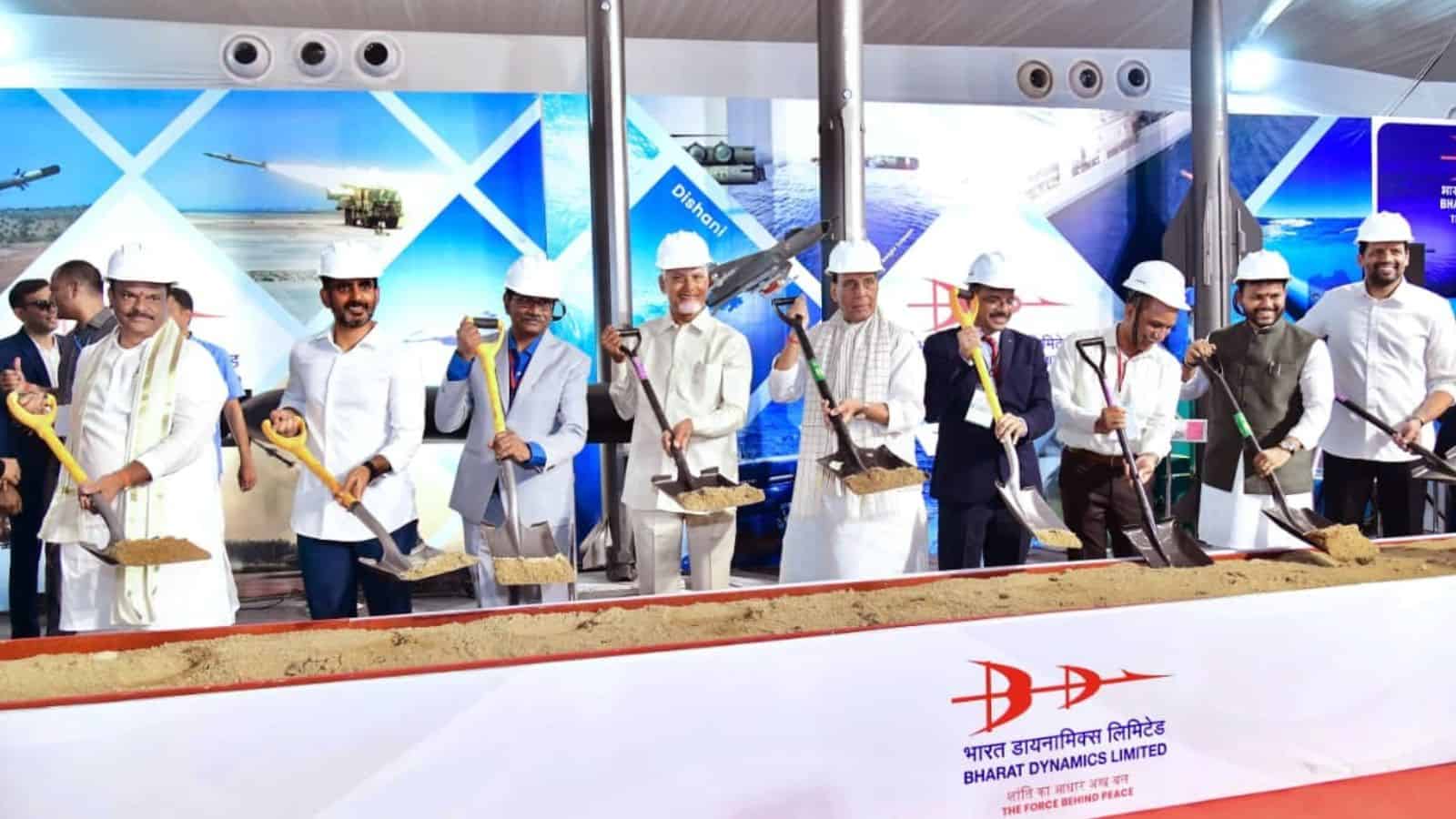 Construction workers at the Siasat Daily event in India, wearing white helmets and uniforms, participatin.