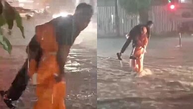 Flooded street with two people wading through water during heavy rain, urban scene with wet pavement and.