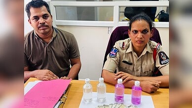 A woman police officer and a man sitting at a desk with hand sanitizers and documents.