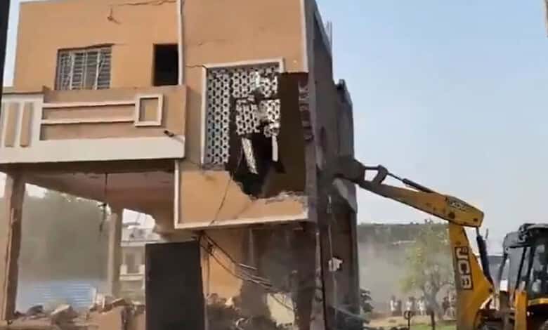 A construction worker operating a JCB excavator demolishing a building in an urban area.