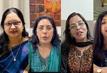 A woman speaking at a press conference with three other women, all dressed in traditional Indian attire,.