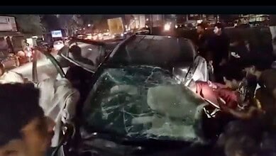 Car crash at night with multiple damaged vehicles and emergency responders on busy city street.
