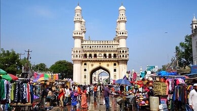 Colourful street market scene with the Charminar in Hyderabad, India, bustling with vendors, shoppers, an.