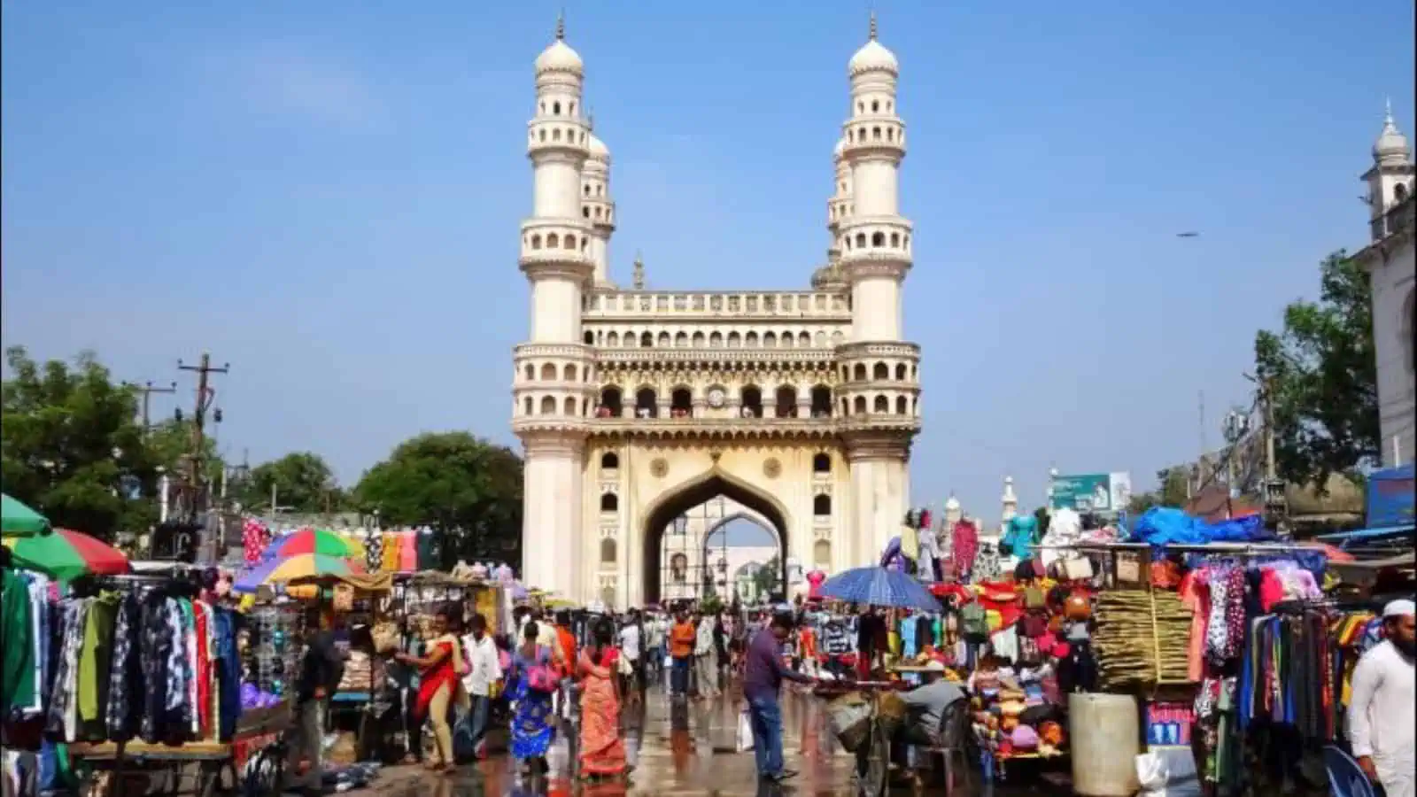 Colourful street market scene with the Charminar in Hyderabad, India, bustling with vendors, shoppers, an.