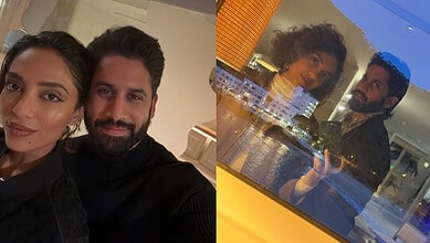 Couple capturing a selfie together at night, reflecting city lights and skyline through a glass window.