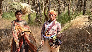 Chenchu tribe members in forest, holding grass and traditional tools, highlighting indigenous lifestyle a.