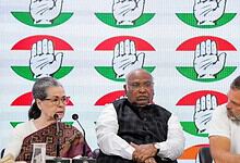 Indian political leaders at a press conference with the Congress party symbol in the background.