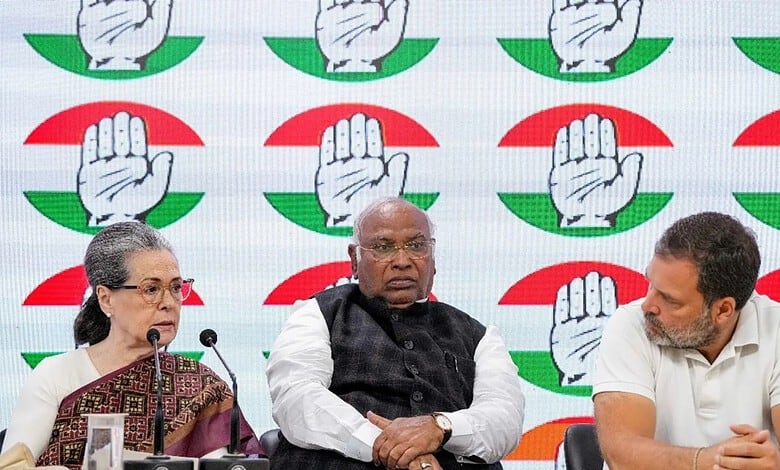 Indian political leaders at a press conference with the Congress party symbol in the background.