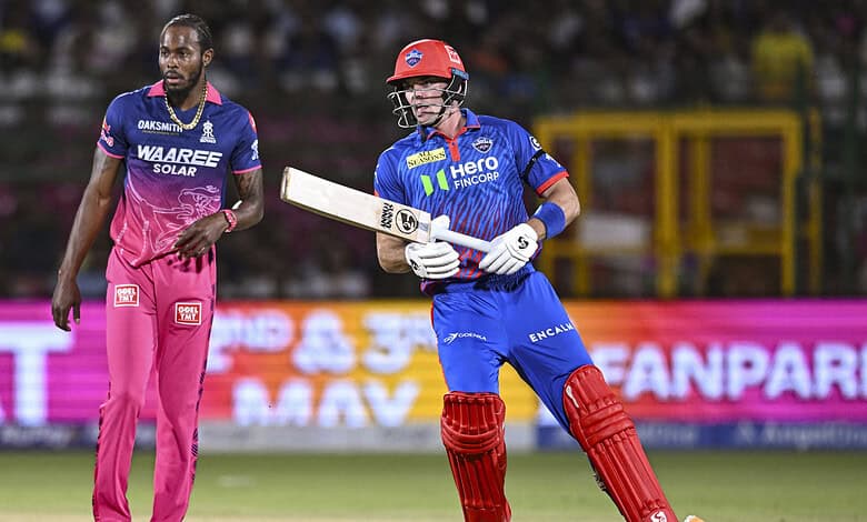 Cricket player in blue and red uniform holding bat on the field during IPL 2026 match.