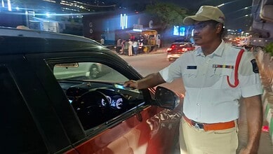 Police officer checking driver for alcohol consumption during a night crackdown.