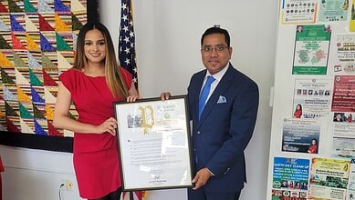 Woman and man holding a framed award at an office event.