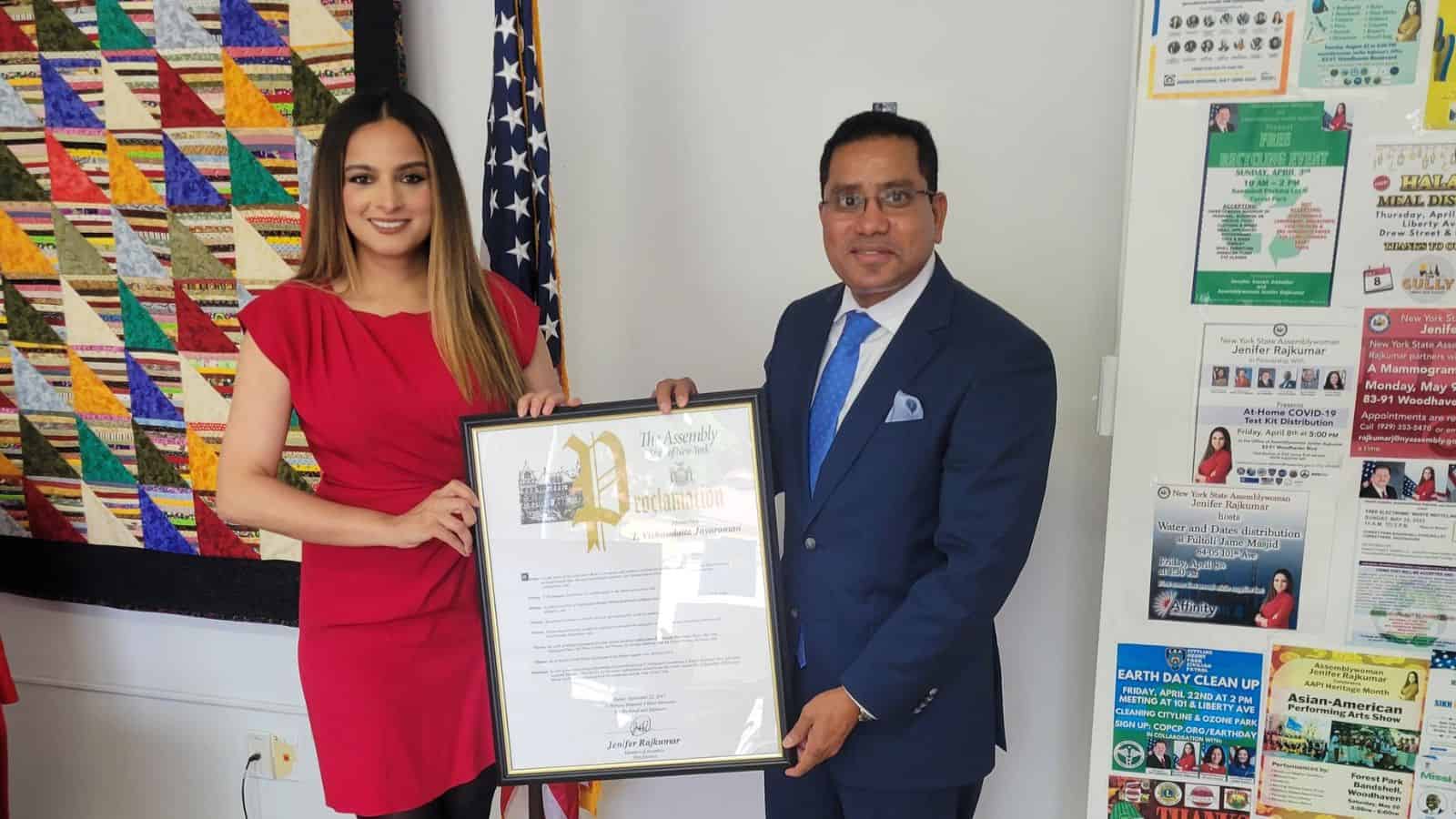 Woman and man holding a framed award at an office event.