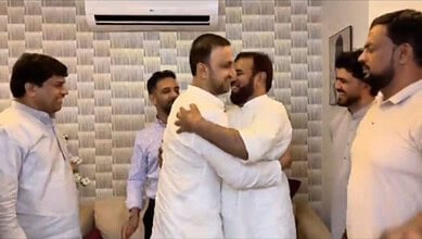 Group of men embracing and smiling in a modern indoor setting, showcasing friendship and unity.