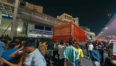 A busy street scene at night with a large red truck and a crowd of people in front of the Office of the D.