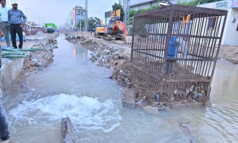 Flooded construction site with workers and machinery during heavy rain in an urban area.