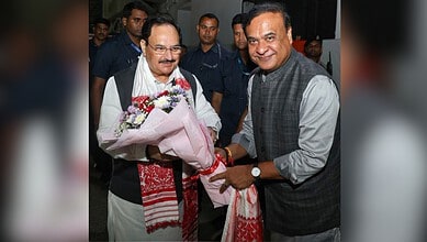 Himanta Biswa Sarma with supporters, holding a bouquet, at a political event in Assam.