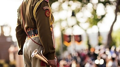 A soldier in uniform holding a ceremonial trumpet during a public event or parade.