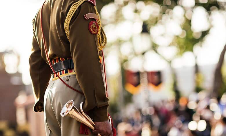 A soldier in uniform holding a ceremonial trumpet during a public event or parade.