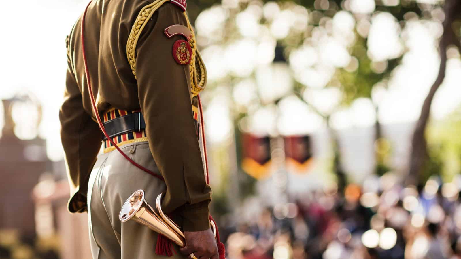 A soldier in uniform holding a ceremonial trumpet during a public event or parade.