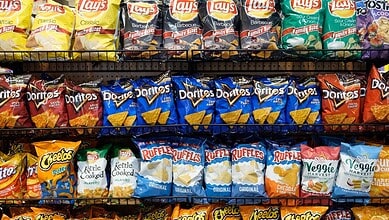 A colourful assortment of snack chips including Lay's, Doritos, Cheetos, Ruffles, and Veggie Harvest on s.