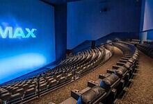 IMAX theatre interior with rows of plush seats and a large screen displaying the IMAX logo, ready for a c.
