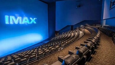 IMAX theatre interior with rows of plush seats and a large screen displaying the IMAX logo, ready for a c.