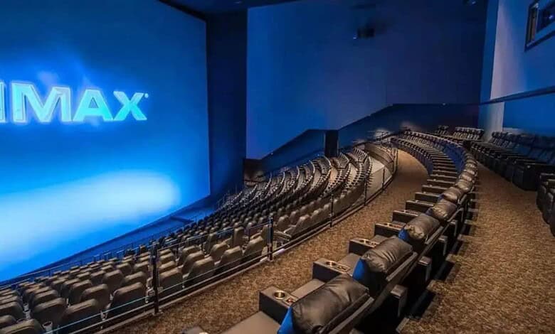 IMAX theatre interior with rows of plush seats and a large screen displaying the IMAX logo, ready for a c.
