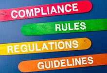 Colourful wooden sticks with the words "Compliance," "Rules," "Regulations," and "Guidelines" on a blue b.