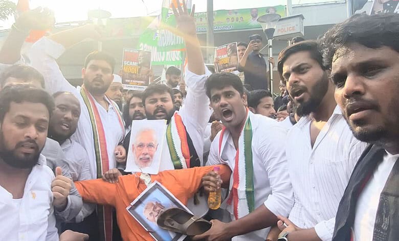 Protesters holding banners and a portrait of Narendra Modi during a rally in India.