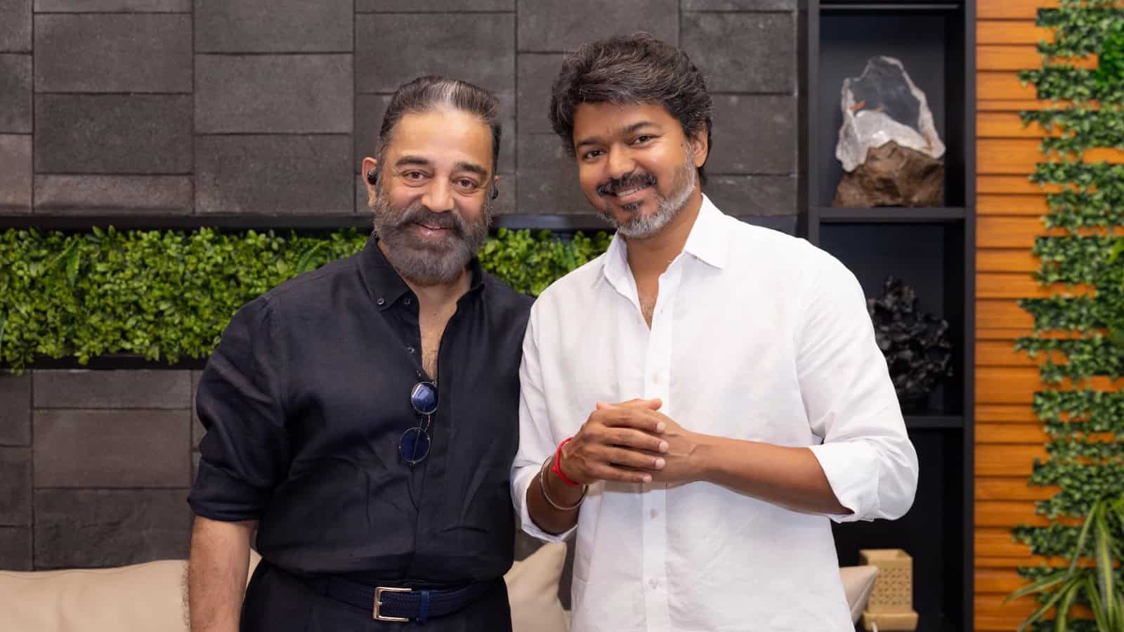 A man in a black shirt and a man in a white shirt smiling together indoors.