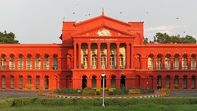 Historic red building with classical architecture, featuring columns and ornate details, set against a cl.