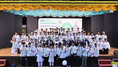 Students celebrating graduation at an indoor ceremony with a large group photo.