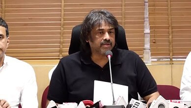 Prominent speaker at a press conference addressing media questions in a professional setting.