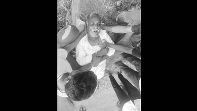 A woman lying on the ground surrounded by several people, appearing distressed or in need of assistance.